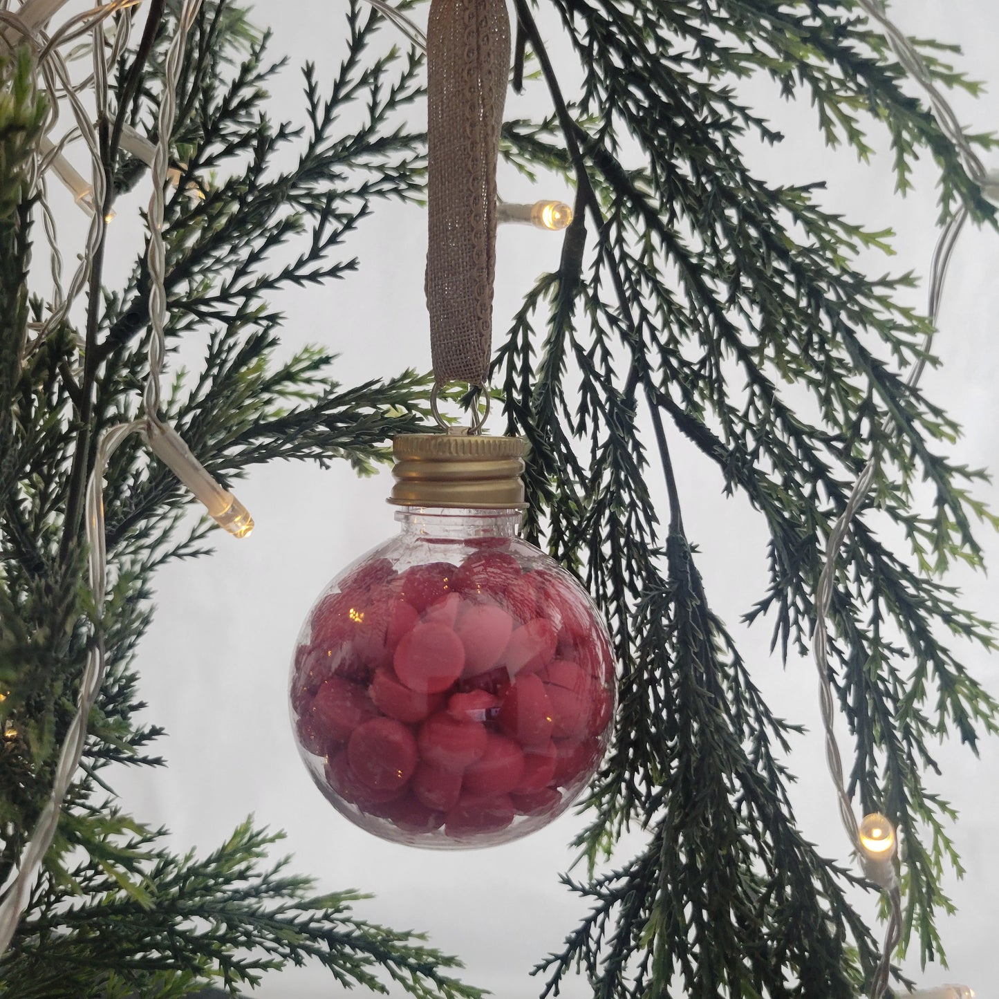 Berry + Bright ornament filled with 2 oz of beaded coconut wax melts, hanging on a Christmas tree as a festive holiday decoration.