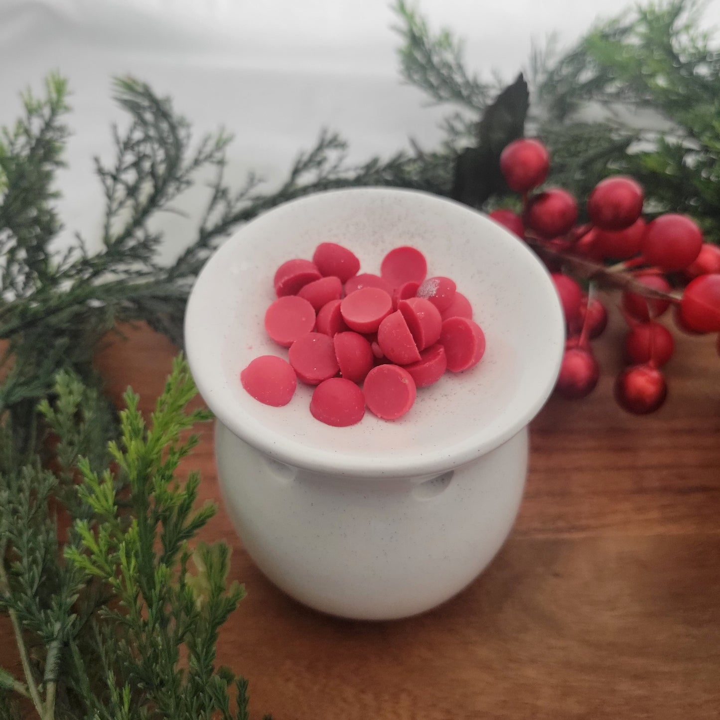 Berry + Bright coconut wax melt beads from ornament placed in an electric wax warmer, releasing festive cranberry, currant, and pine fragrance.