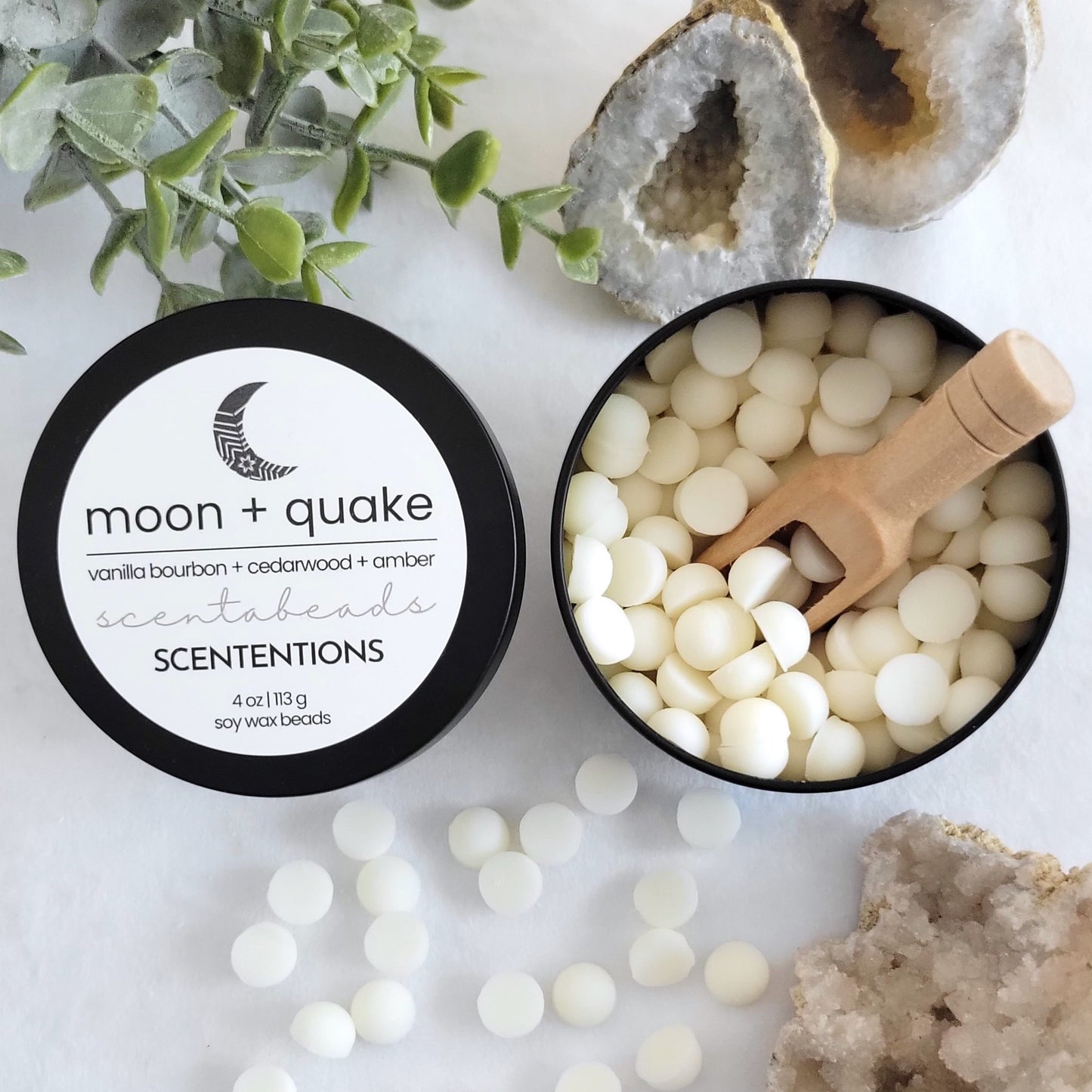 Moon + Quake wax melt beads in eco-conscious tin with grounding warm scent and wooden scoop by Scententions.