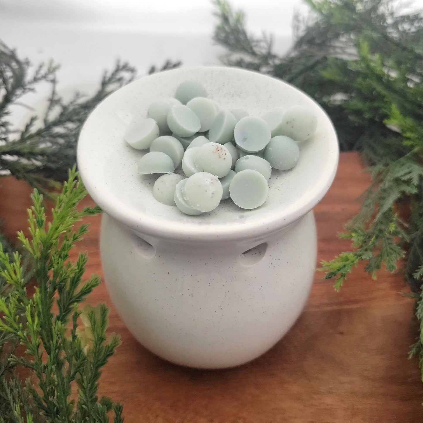 Winter + Wishes coconut wax melt beads from ornament placed in an electric wax warmer, releasing balsam, eucalyptus, and sandalwood fragrance.