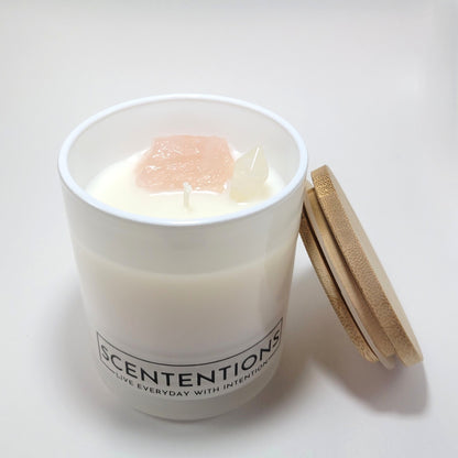 Coasts + Coconuts Wanderlust crystal coconut wax candle in clear glass vessel with bamboo lid beside jar on white background.