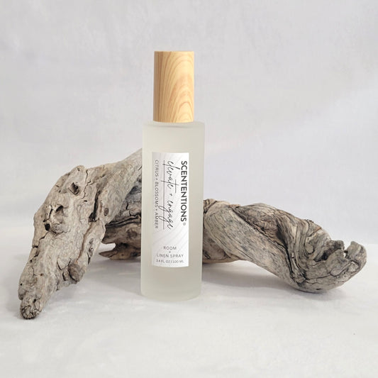 Frosted glass room and linen spray bottle labeled Elevate + Engage on a natural wood background.