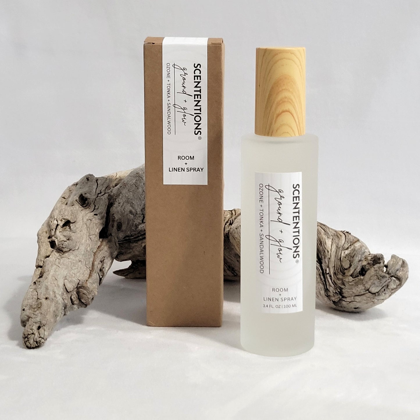 Ground + Glow room and linen spray shown with its packaging box on a natural wood background.
