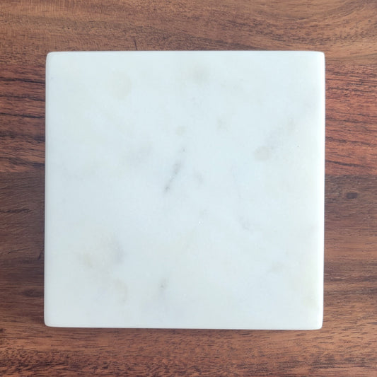 Close-up of smooth square marble candle coaster made from white stone