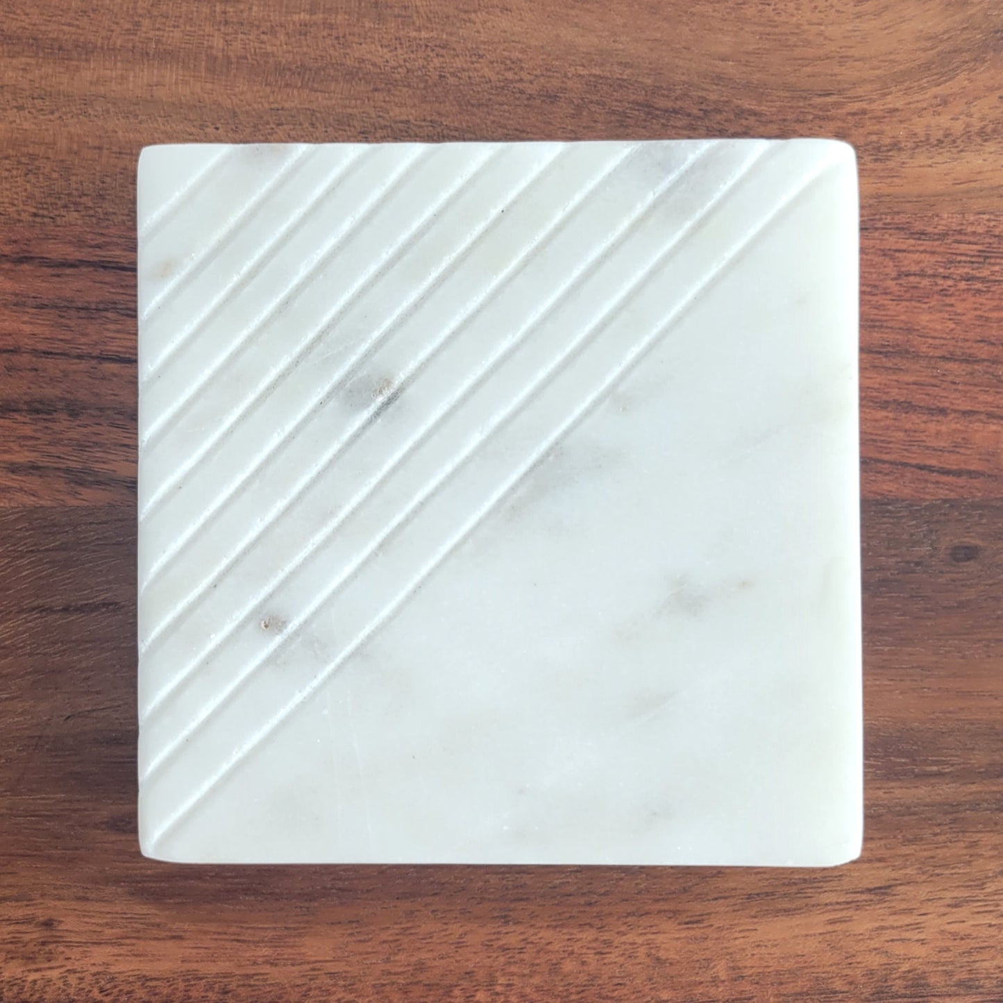 Close-up of square lined marble candle coaster made from white stone