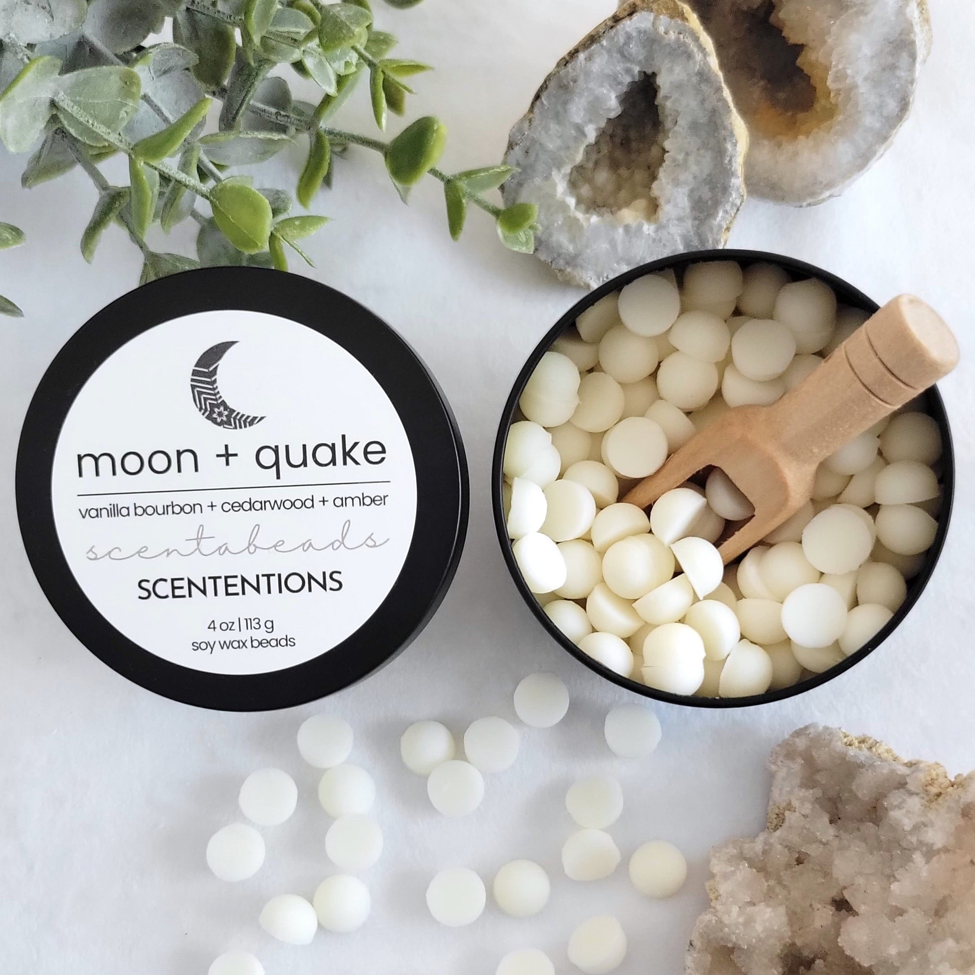 Moon + Quake wax melt beads in eco-conscious tin with grounding warm scent and wooden scoop by Scententions.