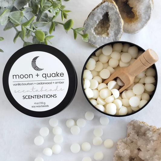 Moon + Quake wax melt beads in eco-conscious tin with grounding warm scent and wooden scoop by Scententions.