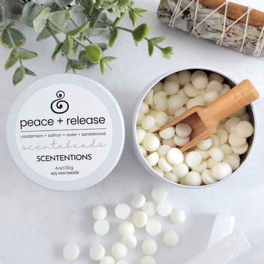 Peace + Release wax melt beads in tin container with reusable wooden scoop