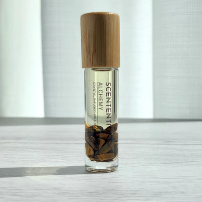 Crystal infused roll-on essential oil with Tiger’s Eye crystals and bamboo lid on white wood surface in natural light