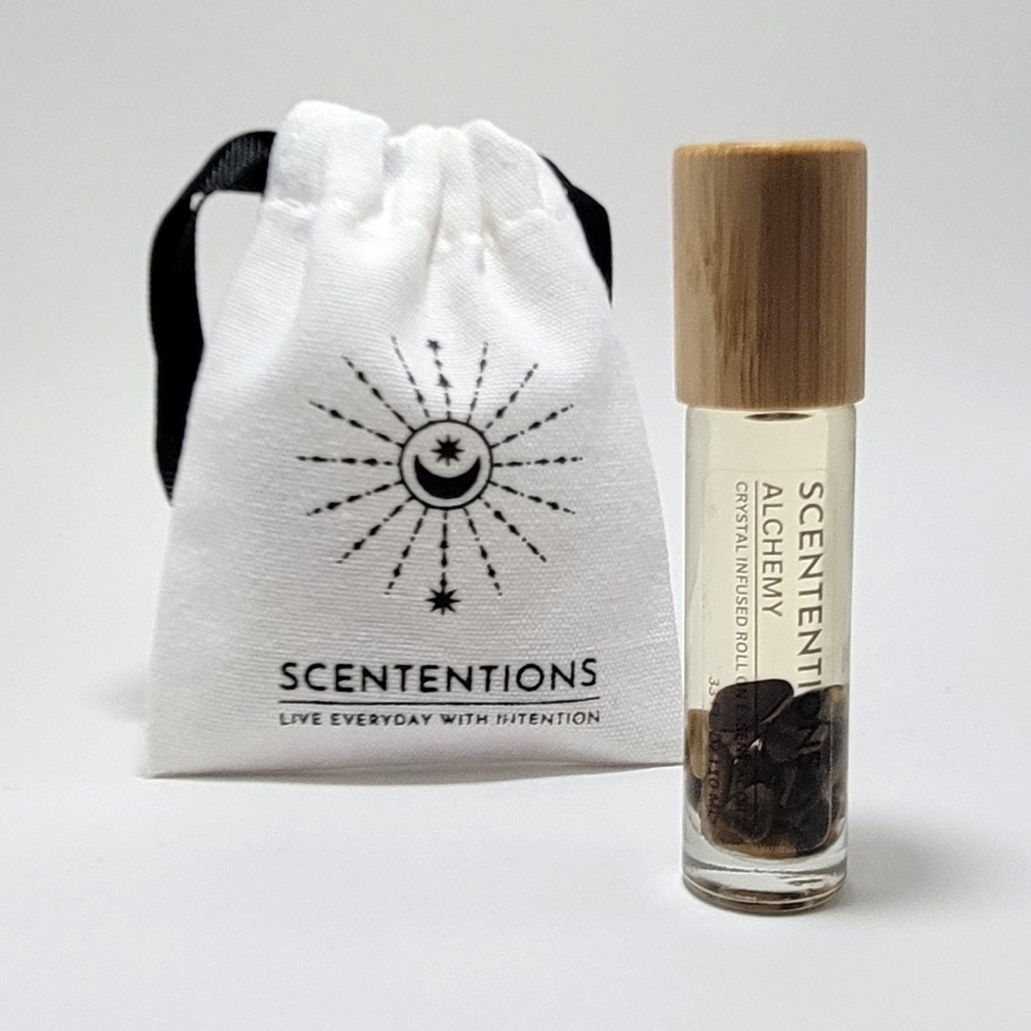 Crystal infused roll-on essential oil with Tiger’s Eye crystals next to Scententions canvas pouch