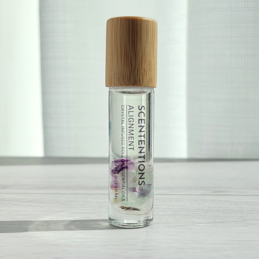 Crystal infused roll-on essential oil with Fluorite crystals and bamboo lid on white wood surface in natural light