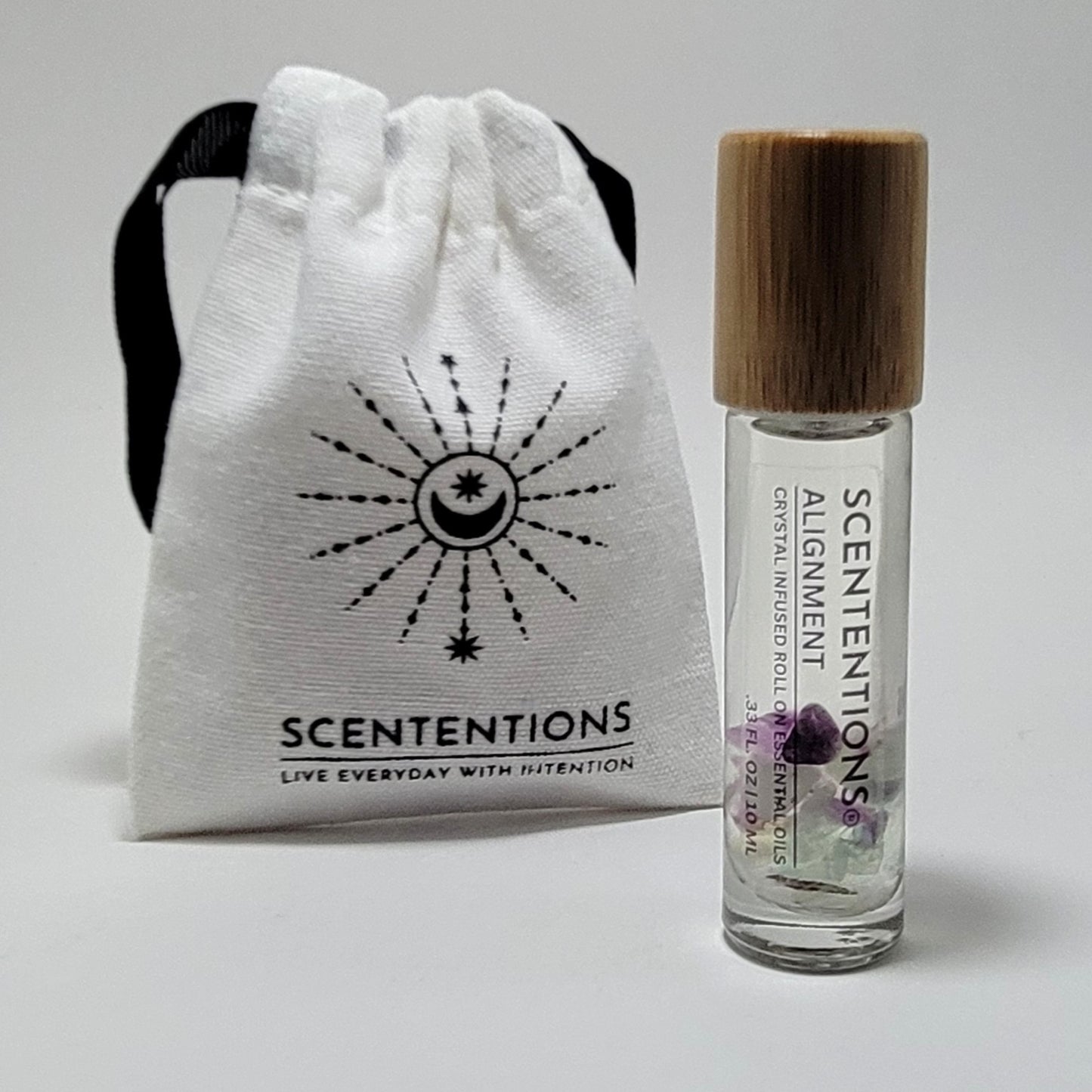 Crystal infused roll-on essential oil with Fluorite crystals next to Scententions canvas pouch