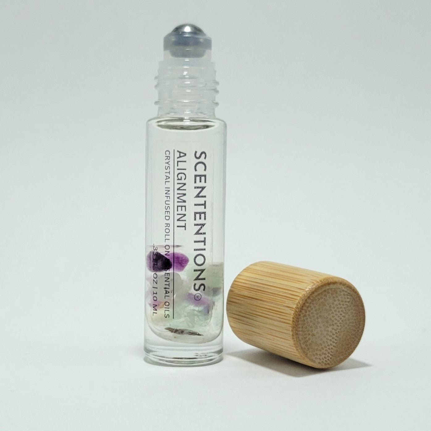 Open crystal infused roll-on bottle with visible Fluorite crystals and bamboo cap beside it