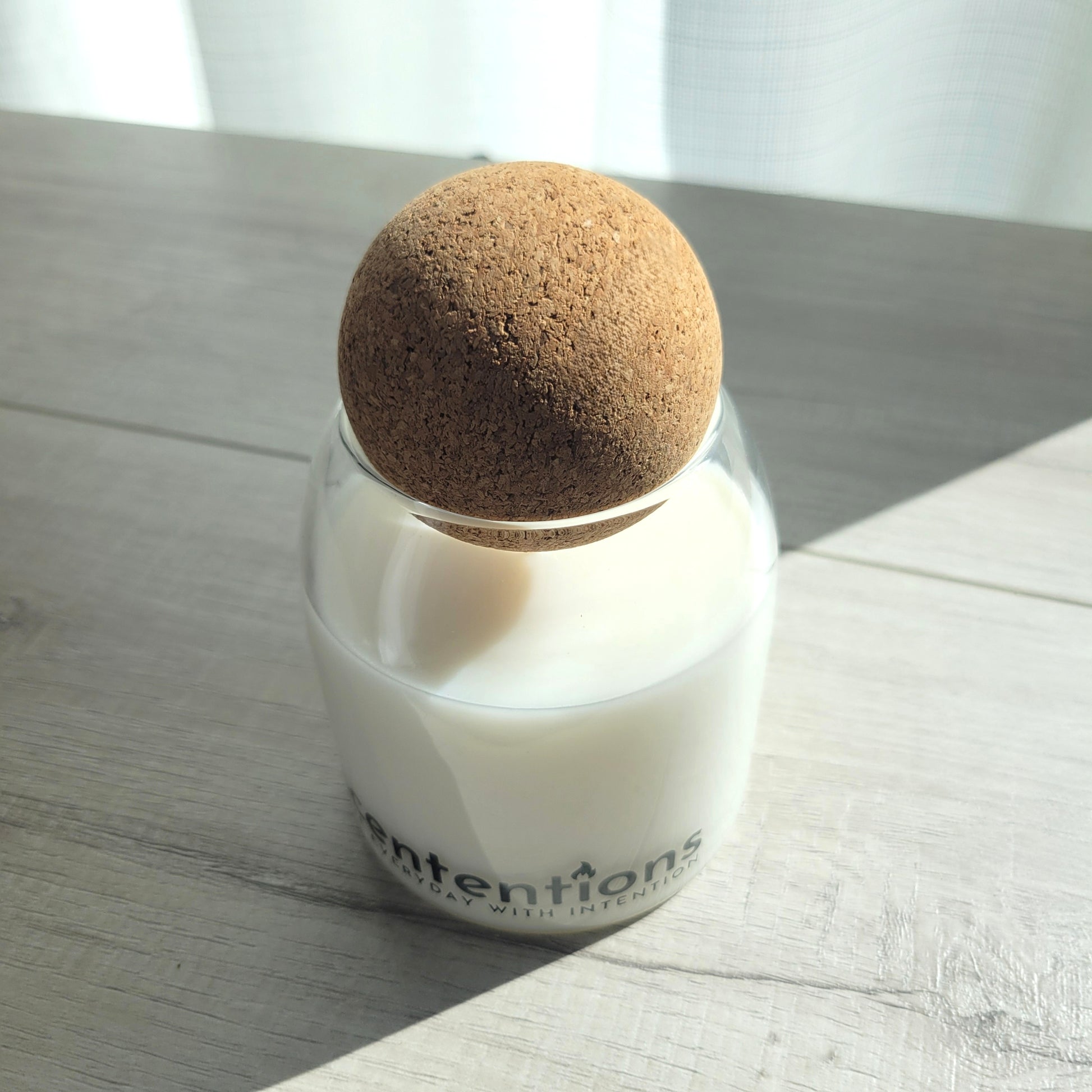 Awaken + Align signature coconut wax candle in clear glass vessel with cork lid, featuring marine and sandalwood notes.