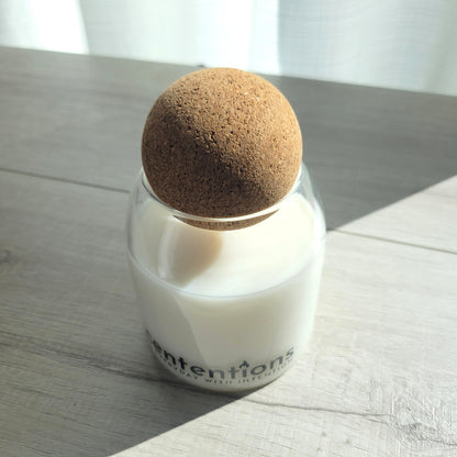 Awaken + Align signature coconut wax candle in clear glass vessel with cork lid, featuring marine and sandalwood notes.