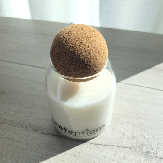 Awaken + Align signature coconut wax candle in clear glass vessel with cork lid, featuring marine and sandalwood notes.