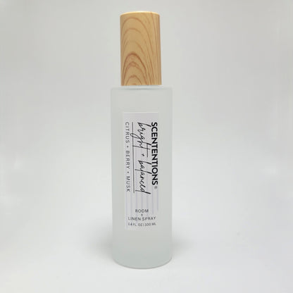 Bright + Balanced room and linen spray in frosted glass bottle with wood cap on white background.