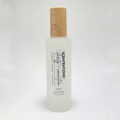 Clarity + Connection room and linen spray in frosted glass bottle with wood cap on white background.