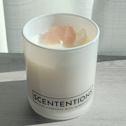 Coasts + Coconuts Wanderlust crystal coconut wax candle in clear glass vessel with rose quartz and clear quartz crystals in natural sunlight.