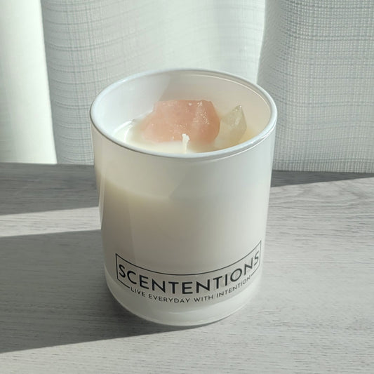 Coasts + Coconuts Wanderlust crystal coconut wax candle in clear glass vessel with rose quartz and clear quartz crystals in natural sunlight.