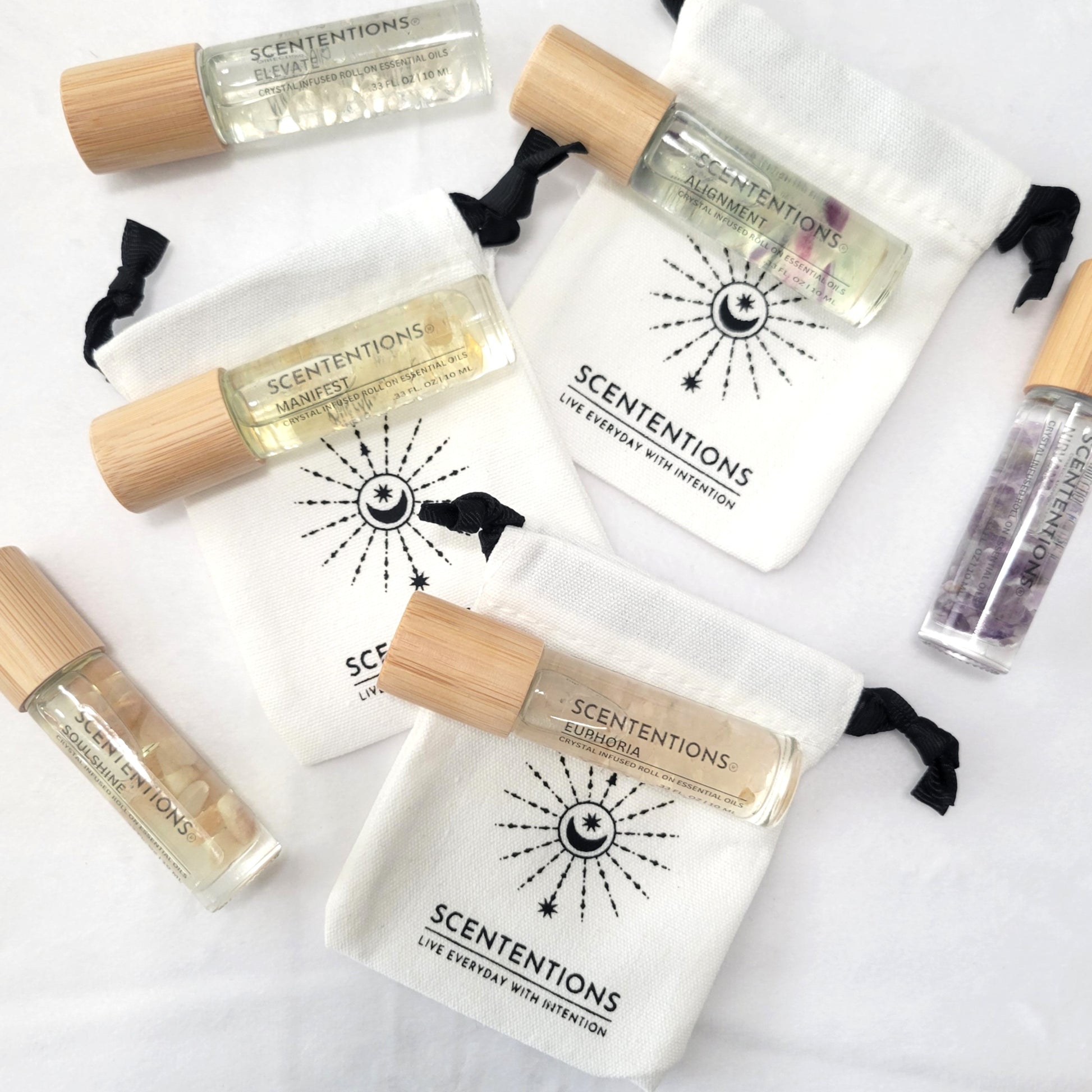 Crystal infused essential oil roll-on collection with bamboo lids and mini canvas bags on natural background