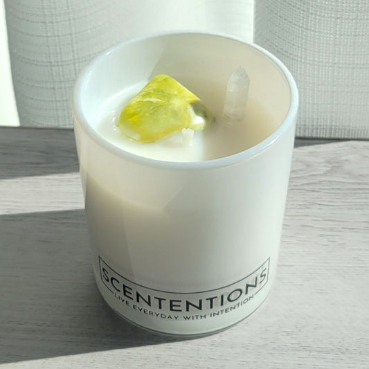 Dream + Discover Wanderlust crystal coconut wax candle in clear glass vessel with noble serpentine and clear quartz double-sided point in natural sunlight.