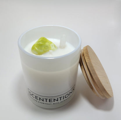 Dream + Discover Wanderlust crystal coconut wax candle with noble serpentine and clear quartz double-sided point and bamboo lid beside jar. 