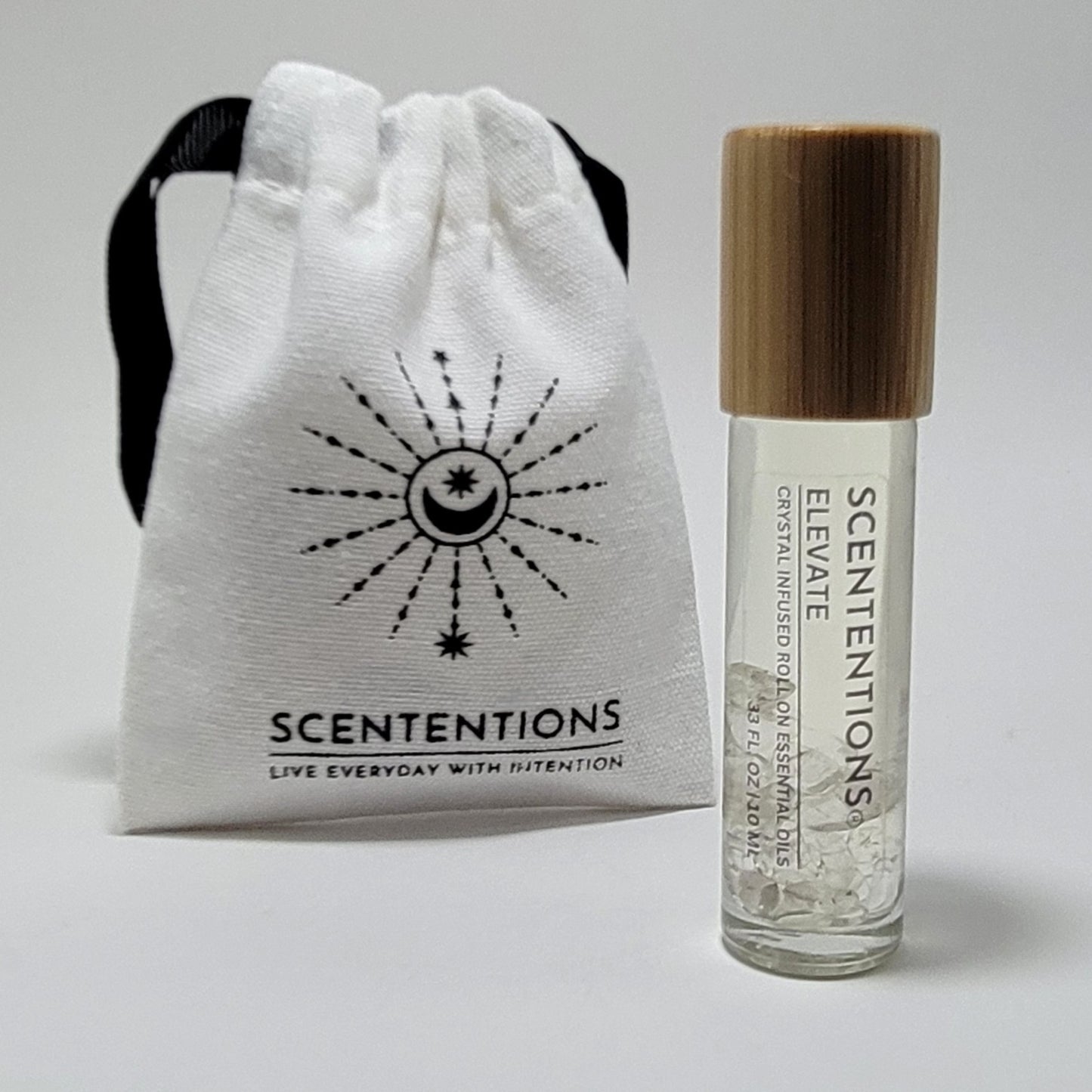 Crystal infused roll-on essential oil with Clear Quartz crystals next to Scententions canvas pouch