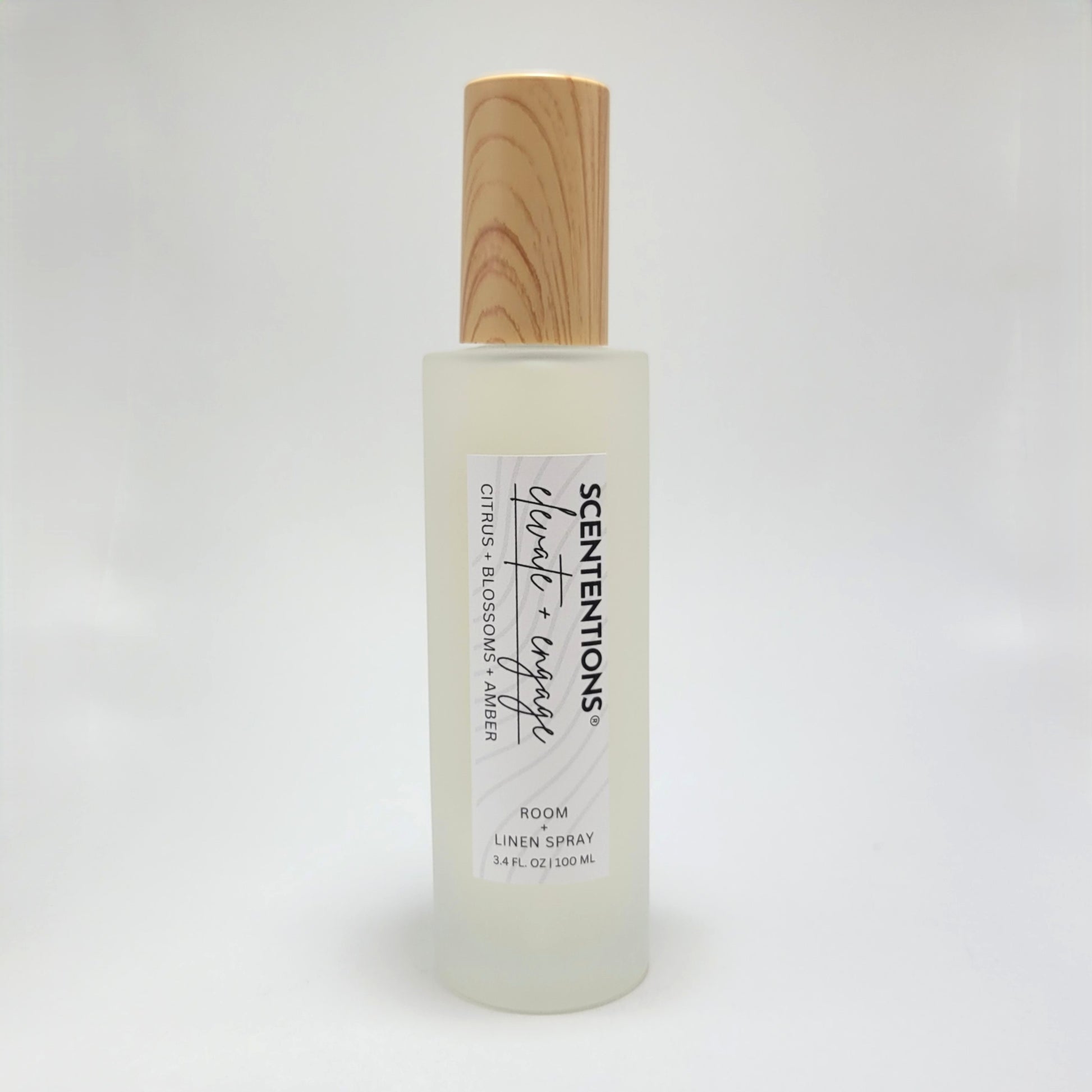 Elevate + Engage room and linen spray in frosted glass bottle with wood cap on white background.