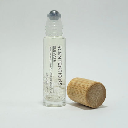 Open crystal infused roll-on bottle with visible Clear Quartz crystals and bamboo cap beside it