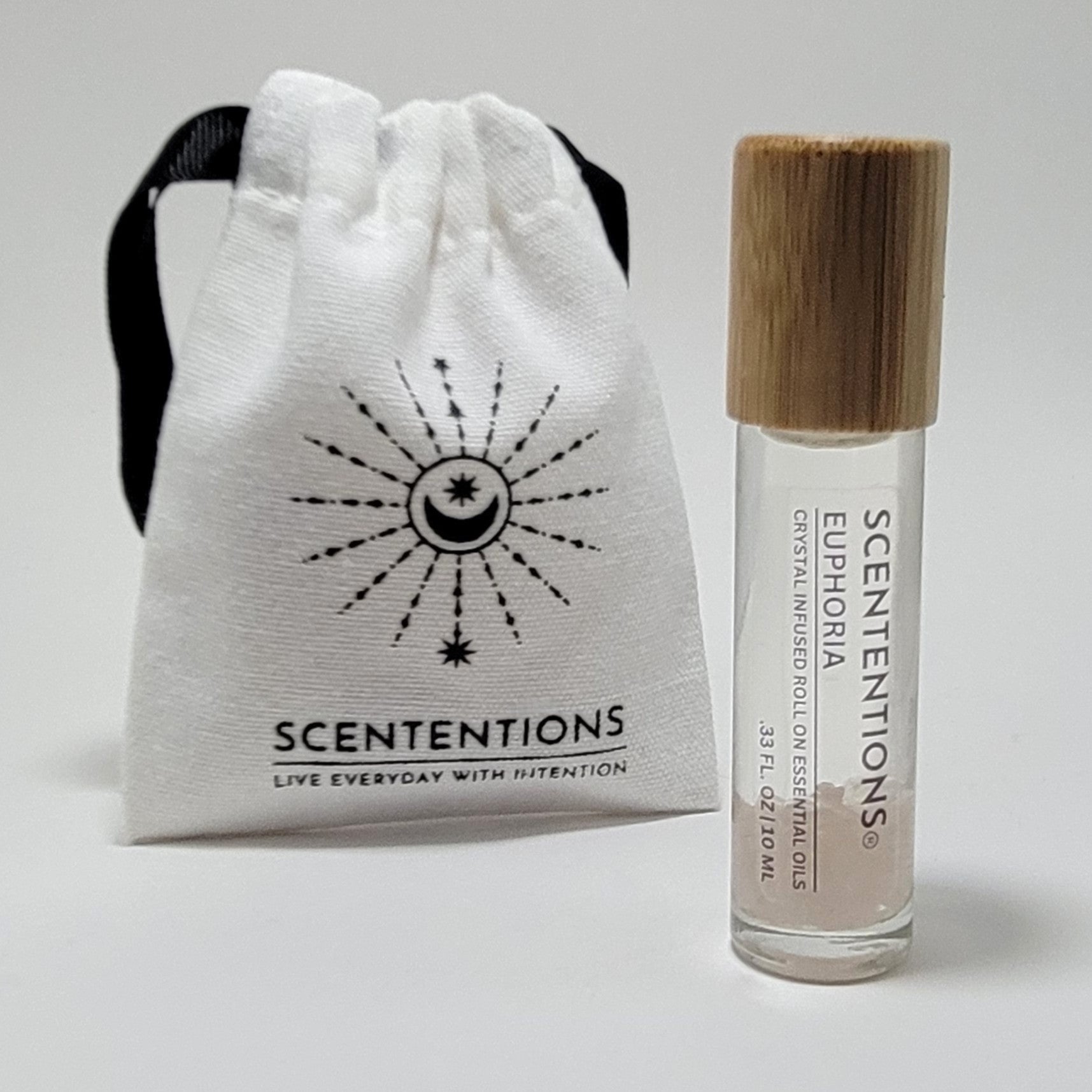 Crystal infused roll-on essential oil with Rose Quartz crystals next to Scententions canvas pouch