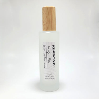 Focus + Flow room and linen spray in frosted glass bottle with wood cap on white background.