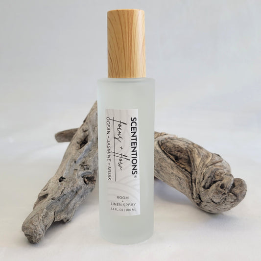 Focus + Flow room and linen spray in frosted glass bottle styled with natural driftwood.