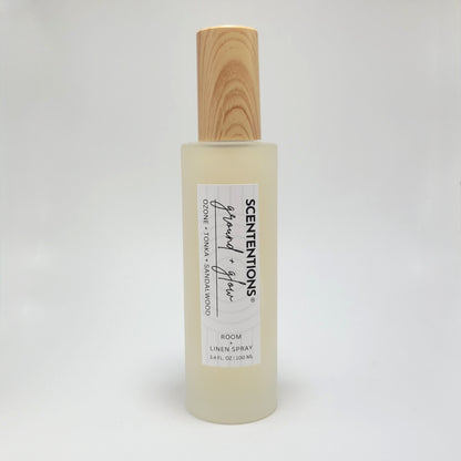 Ground + Glow room and linen spray in frosted glass bottle with wood cap on white background.