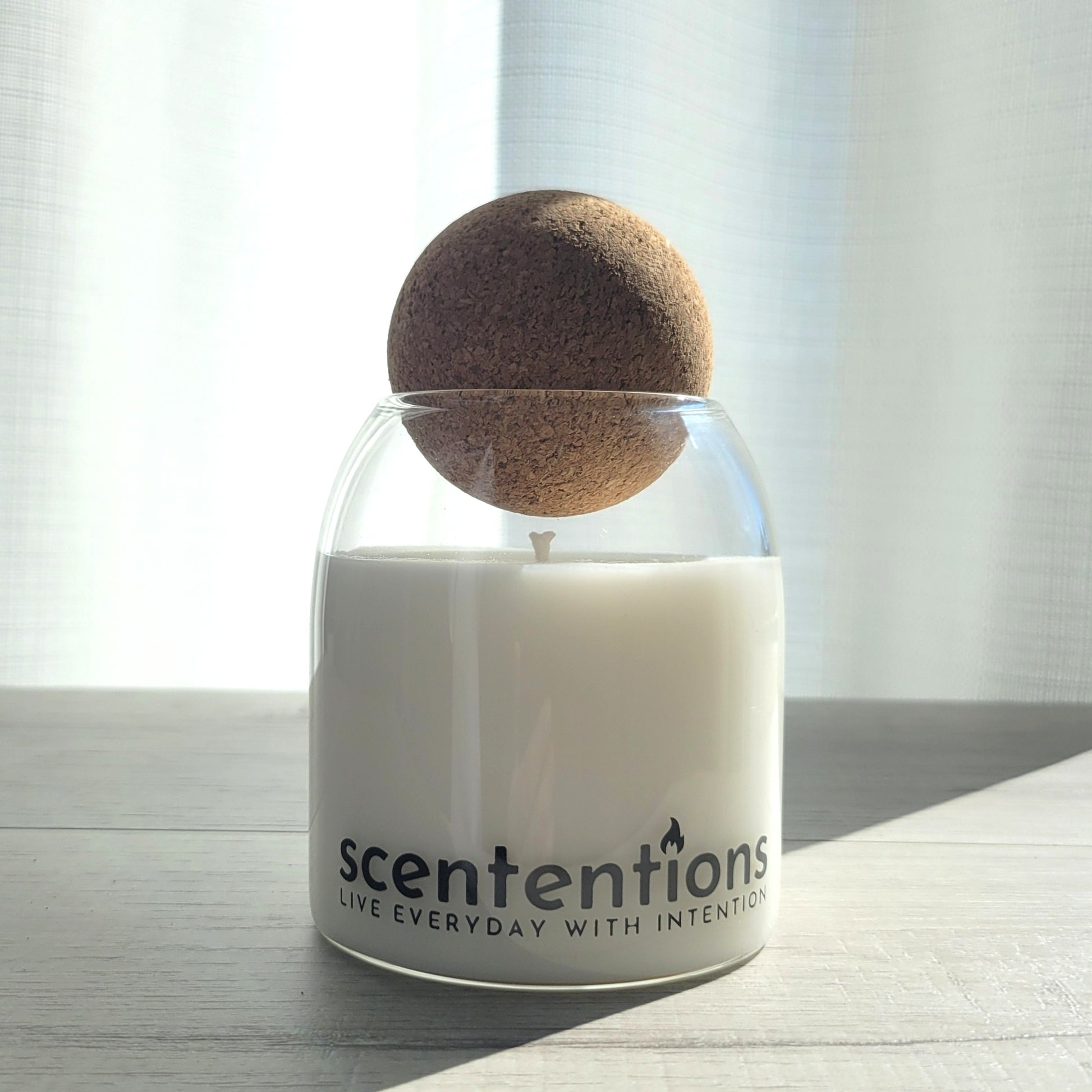 Love + Light signature coconut wax candle in clear glass vessel with cork lid, featuring honey and rose notes.