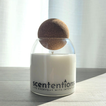 Love + Light signature coconut wax candle in clear glass vessel with cork lid, featuring honey and rose notes.