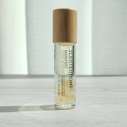 Crystal infused roll-on essential oil with Citrine crystals and bamboo lid on white wood surface in natural light