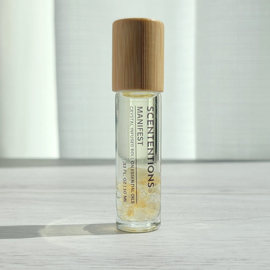 Crystal infused roll-on essential oil with Citrine crystals and bamboo lid on white wood surface in natural light