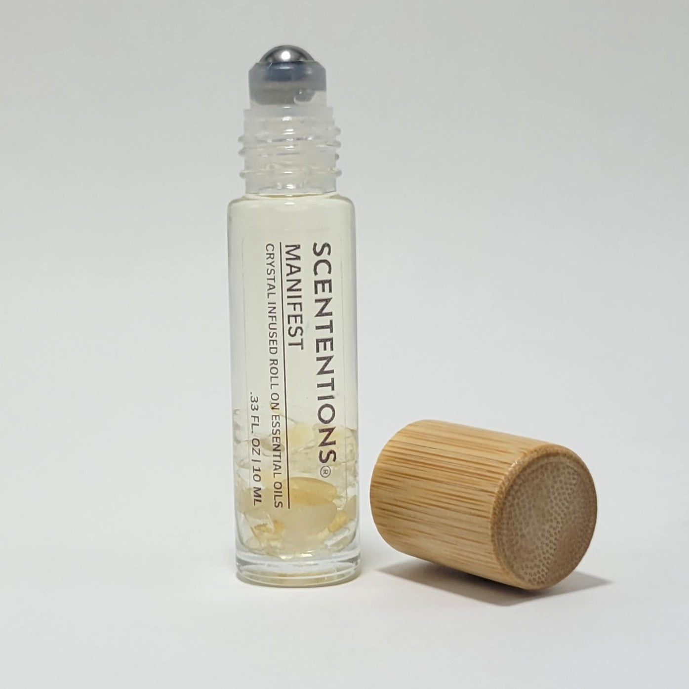 Open crystal infused roll-on bottle with visible Citrine crystals and bamboo cap beside it