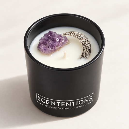 SCENTENTIONS Moon + Bloom 7 oz coconut wax candle in matte black vessel with raw amethyst crystal and silver crescent moon charm.