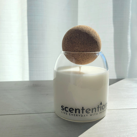 Peace + Release signature coconut wax candle in clear glass vessel with cork lid, featuring palo santo and amber notes.