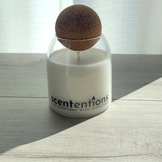 Relax + Reset signature coconut wax candle in clear glass vessel with cork lid, featuring lavender and sage notes.