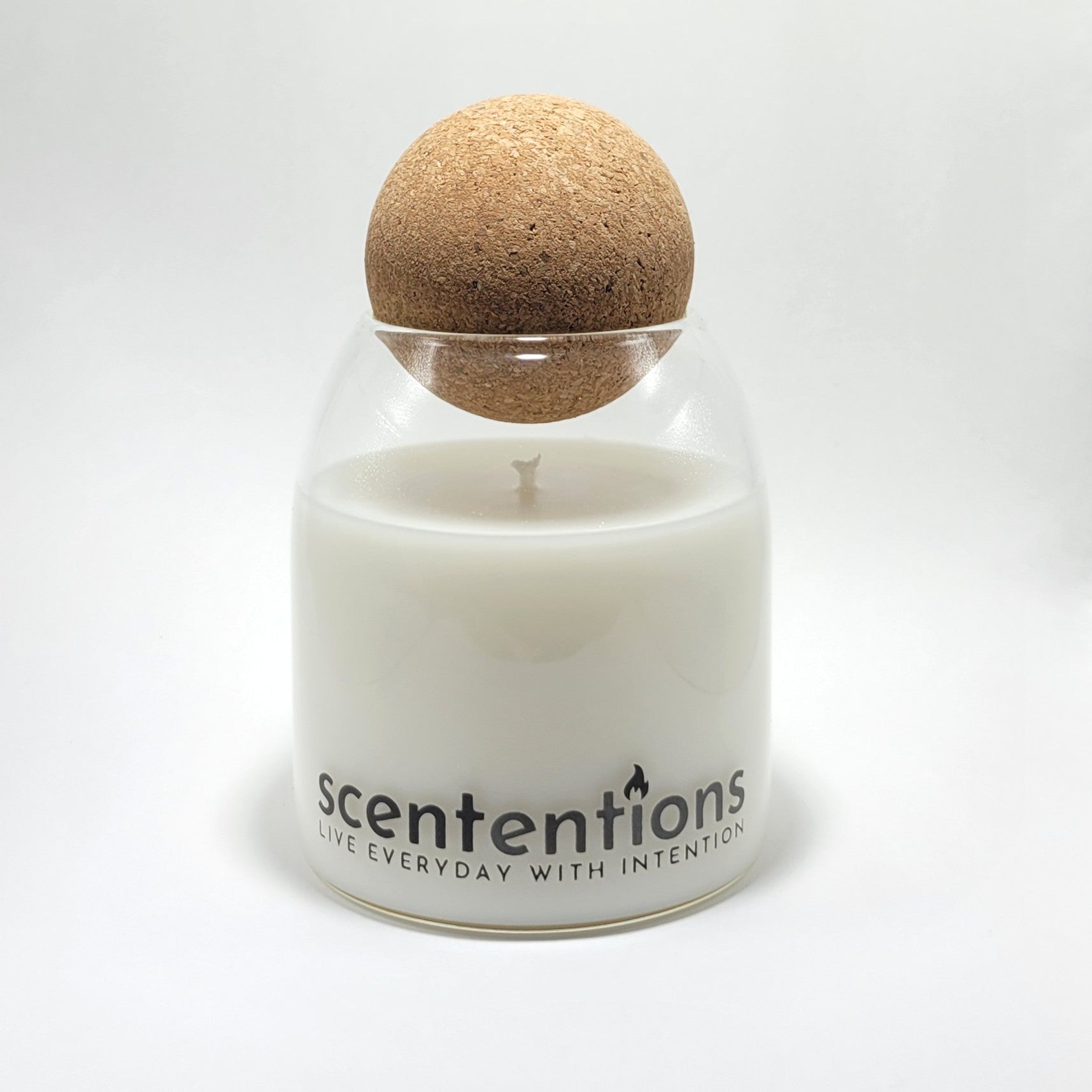 Signature coconut wax candle in clear glass vessel with cork lid on white background.