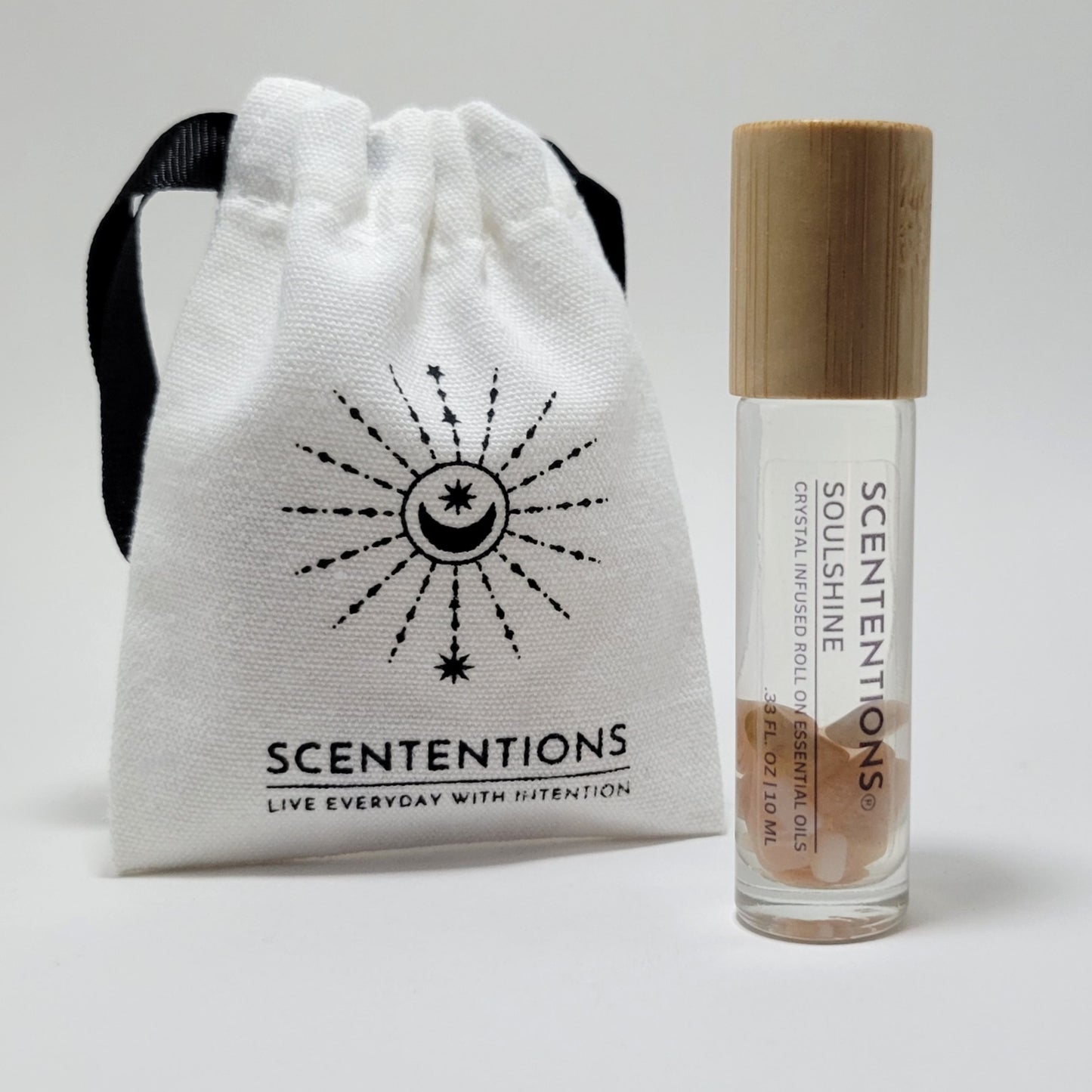 Crystal infused roll-on essential oil with Sunstone crystals next to Scententions canvas pouch.