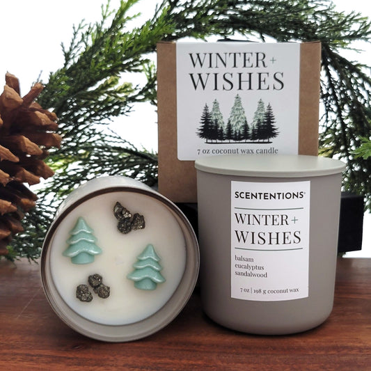 Winter + Wishes holiday candle with balsam, eucalyptus, and sandalwood. Shown with gift box, vessel, and candle top with Christmas tree wax embeds and pyrite crystals.